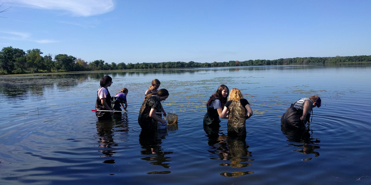 8th graders wading in water to take samples.